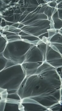 Abstract background of caustic light patterns reflecting on the surface of dark water.