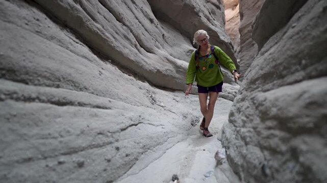 A senior woman is happy while hiking through a slot canyon in Anza Borego State Park, exploring the desert trails and scenery.