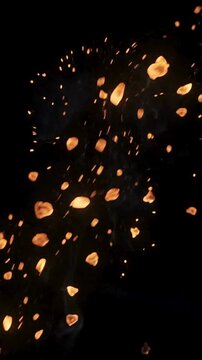 Bright glowing orange sparks flying upwards against a dark black background.