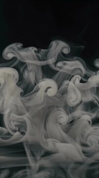 Abstract white smoke swirls rising against a dark black background.