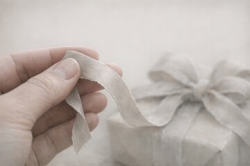 A person holding a piece of cloth or paper next to a wrapped gift box