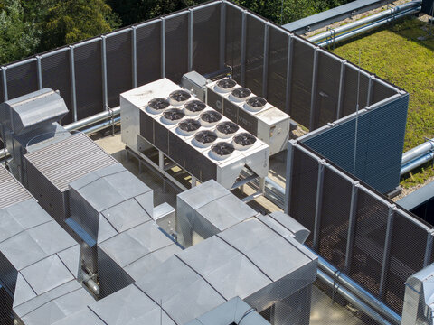 Krakow, Poland - 04 August 2026: Aerial view of an AI data center cooling system featuring industrial fans and metal ductwork on a rooftop, surrounded by protective fencing.