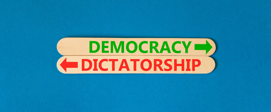 Democracy or dictatorship words symbol. Concept words Democracy Dictatorship on beautiful wooden sticks. Beautiful blue background. Business democracy dictatorship concept. Copy space