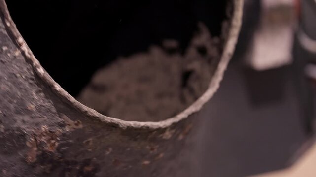 Wet concrete mixture rotating inside concrete mixer drum close up