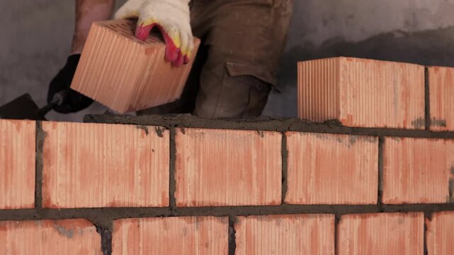 Construction worker with vitiligo laying ceramic brick on mortar