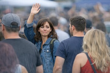 Fototapeta premium A person holding a microphone or instrument waving to the crowd at an outdoor concert