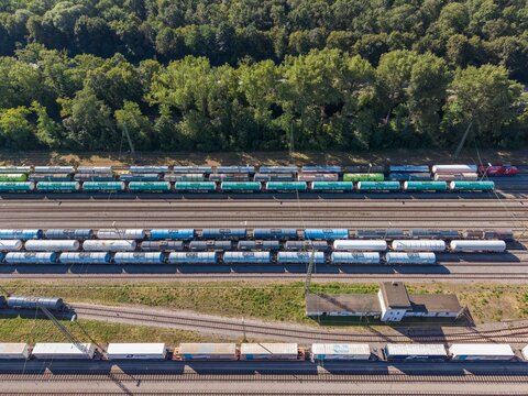 Karlsruhe, Germany - 29 July 2026: Aerial view of a busy freight railway yard with numerous cargo trains parked on parallel tracks, surrounded by lush green trees.