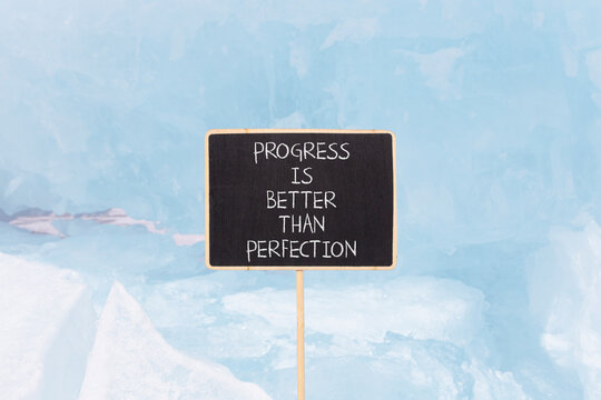 Progress or perfection words symbol. Concept words Progress is better than perfection on beautiful black blackboard. Beautiful blue ice background. Business progress or perfection concept. Copy space.