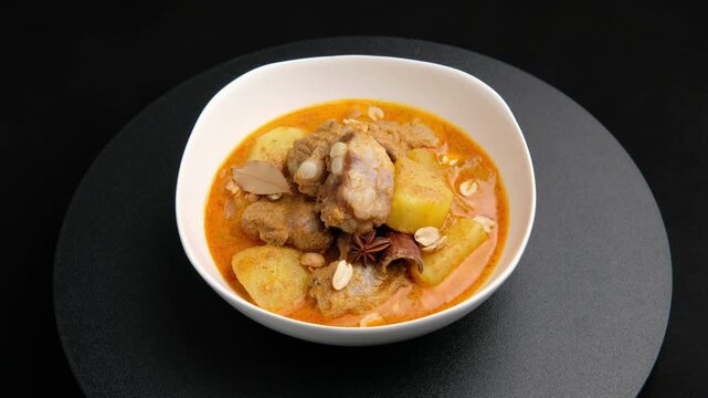 Massaman Curry with baby pork ribs (pork cartilage).Cooked pork meat and potatoes groundnut with massaman curry paste in coconut milk on white bowl.asian food.	