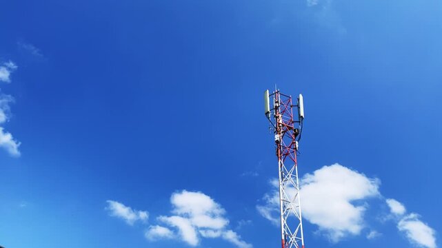 Telecommunications tower rising against blue sky with scattered clouds