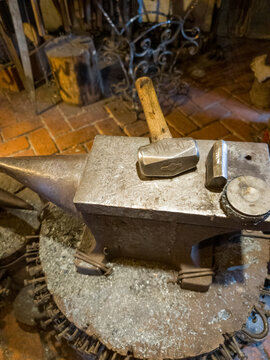 Hammer on anvil in forge on furnace with fire blur background. Smithy workshop and workplace for manufacture of metal structures and for forging hot metal.