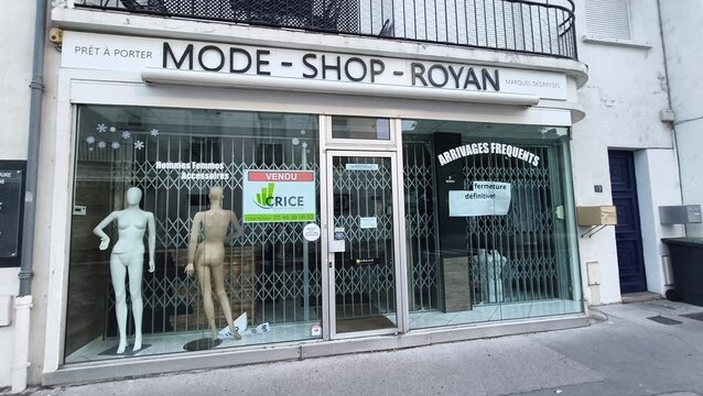 Royan, France - July 15, 2026: Charente-Maritime. Nouvelle-Aquitaine. Fashion shop storefront with mannequins displaying clothing, closed shutters, and sale signs in Royan, France