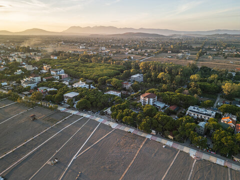 Albania, Velipoja 12 09 2025: Golden hour drone photo of Velipoja beach featuring wooden walkway paths, colorful promenade, hotels in trees, and Ana e Malit mountains.