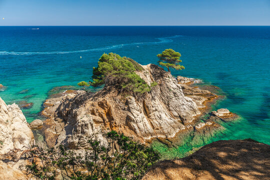 Rocky islet with pine trees and crystal clear Mediterranean waters in Lloret de Mar