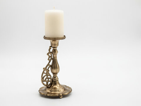 Vintage ornate brass candlestick with unlit white pillar candle isolated on white background 3D rendering