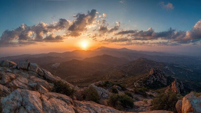 Golden sunrise illuminating rugged mountain peaks over vast rolling