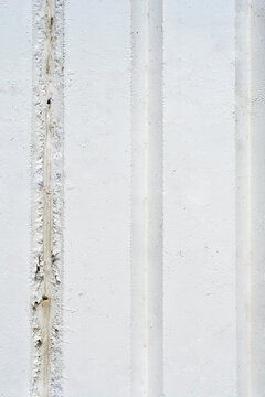 A full frame background texture showing a flat white painted concrete wall surface with parallel vertical grooves and a subtle grain.