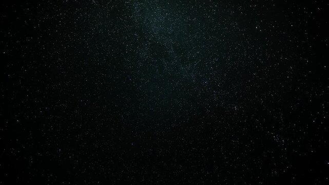 Night sky timelapse of stars moving across a dark sky with meteors and satellites streaking through the sky
