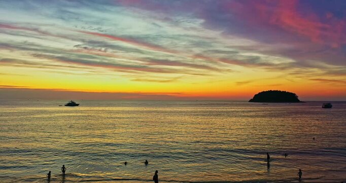 A breathtaking sunset over Pu Island near Kata Beach, Phuket, featuring dramatic red clouds, vibrant orange and purple tones, calm Andaman Sea waters, and tropical island silhouettes. Beautiful image