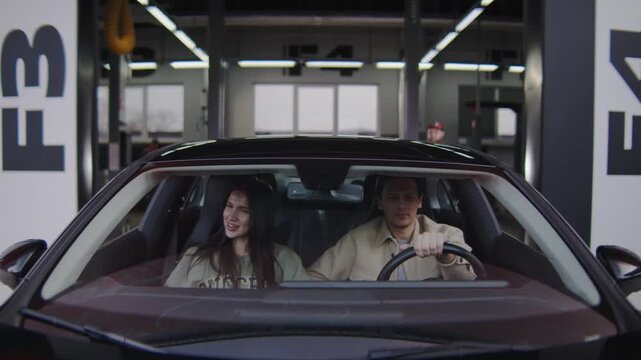 An unusual angle showing a car driving out of a building after a service, with a camera mounted on the hood. 
