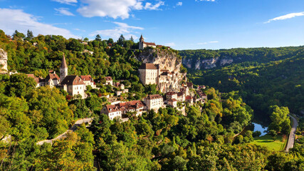 Obraz premium Scenic view of a historic village nestled in the green hills of a valley under a blue sky