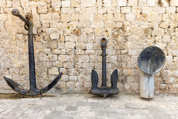 Old anchors and a large funnel stand against a stone wall in Dubrovnik during summer vacation © Point of view