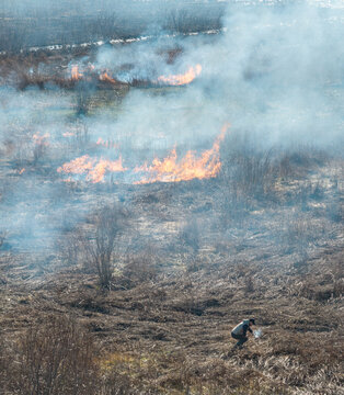 Slanci, City of Belgrade, Serbia - 10 March 2026: Aerial view of a person burning dry vegetation in an agricultural field, creating thick smoke and posing a wildfire risk.