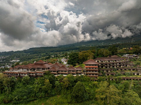 Bedugul, Bali, Indonesia - 10 February 2024: Aerial view of the abandoned Taman Rekreasi Hotel and Resort, known as the Ghost Palace, nestled in lush tropical hills under dramatic clouds.