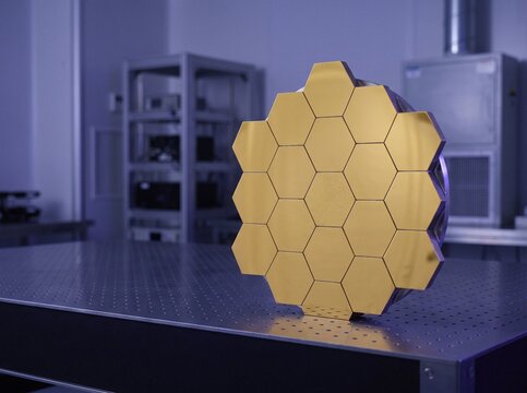 Gold coated hexagonal segmented satellite telescope mirror on optical breadboard table in cleanroom laboratory