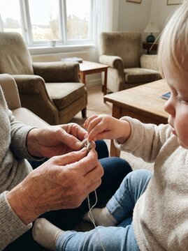 Grandmother teaching small child how to knit with yarn close up representing intergenerational bonding family tradition and learning