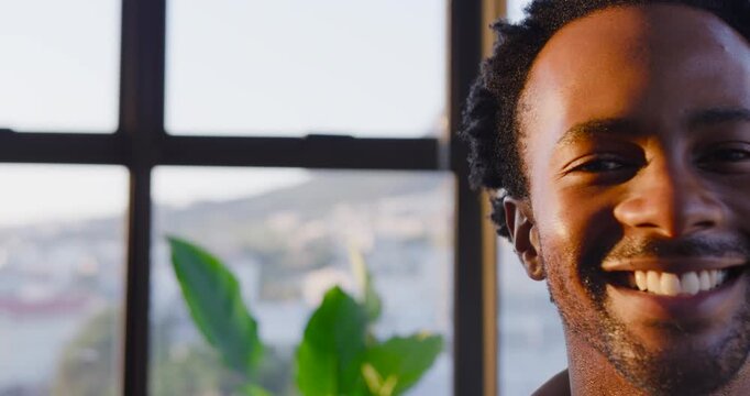 African American man smiling then laughing, responding to off-camera cue at home window, copy space