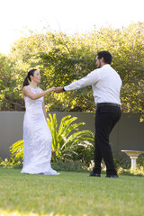 Couple dancing on manicured lawn in private garden with bridal dress and birdbath © wavebreak3