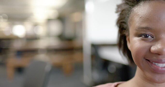 African American woman responding to camera, smiling, widening in study with shelving, copy space