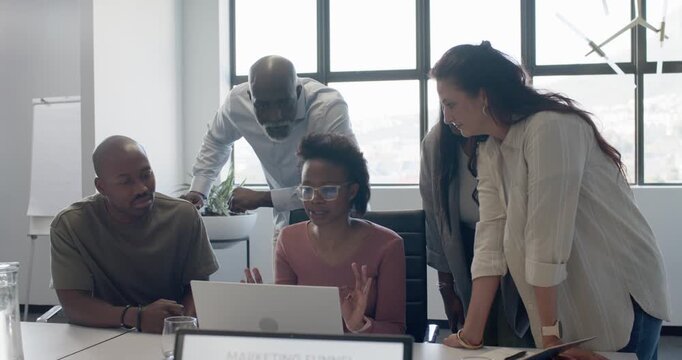 Diverse team gathering as presenter clicking laptop, reviewing marketing funnel in office