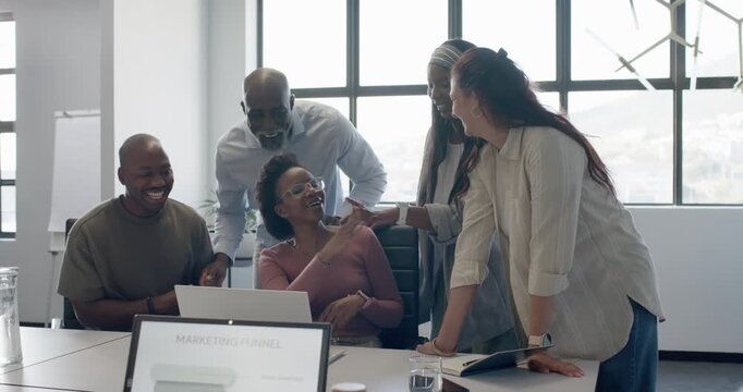 Diverse team in office cheering around woman with glasses at laptop reacting to MARKETING FUNNEL