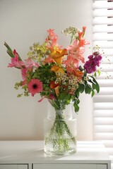Fototapeta premium Bouquet of beautiful summer flowers in vase on cabinet indoors, closeup