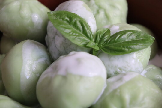 Green dumplings with a basil leaf on top in a close-up view
