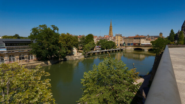 Metz city skyline and Temple Neuf spire reflecting on Moselle river water