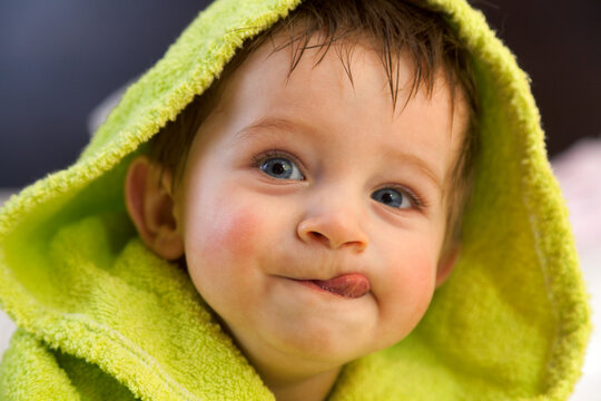 Cute boy in green bathrobe. Shot from above. Looking at the camera, sticking his tongue out