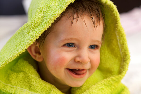 Cute boy in green bathrobe. Shot from above. Looking away from the camera, sticking his tongue out