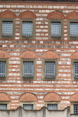 Fototapeta premium Red brick wall with arched windows and metal grilles