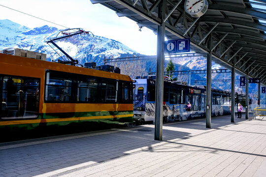 Wengen, Switzerland - March 13, 2026. A passenger train of the Wengernalpbahn cog railway system sits at the covered platform of the Lauterbrunnen railway station. The distinctive yellow and green liv
