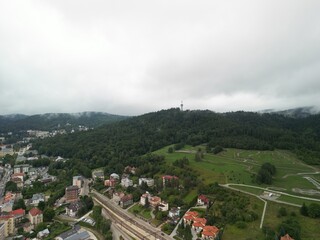 Krynica-Zdrój - Polska Panorama miasta i okolicznych gór nagrana dronem. Jaworzyna Krynicka, Góra Parkowa, miasto, Beskidy, lasy, mgła i chmury nisko osadzone opadające na góry © Konrad
