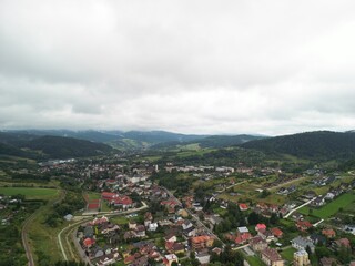 Krynica-Zdrój - Polska Panorama miasta i okolicznych gór nagrana dronem. Jaworzyna Krynicka, Góra Parkowa, miasto, Beskidy, lasy, mgła i chmury nisko osadzone opadające na góry © Konrad