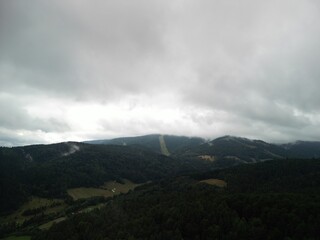 Krynica-Zdrój - Polska Panorama miasta i okolicznych gór nagrana dronem. Jaworzyna Krynicka, Góra Parkowa, miasto, Beskidy, lasy, mgła i chmury nisko osadzone opadające na góry © Konrad