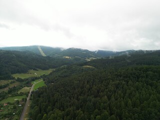 Krynica-Zdrój - Polska Panorama miasta i okolicznych gór nagrana dronem. Jaworzyna Krynicka, Góra Parkowa, miasto, Beskidy, lasy, mgła i chmury nisko osadzone opadające na góry © Konrad