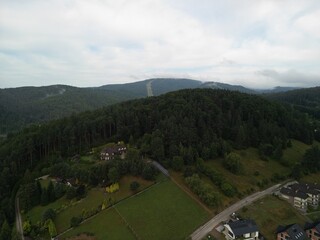 Krynica-Zdrój - Polska Panorama miasta i okolicznych gór nagrana dronem. Jaworzyna Krynicka, Góra Parkowa, miasto, Beskidy, lasy, mgła i chmury nisko osadzone opadające na góry © Konrad