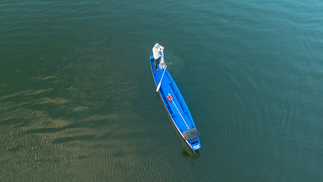Aerial View of Traditional Fisherman Casting a Fishing Net from a Small Boat