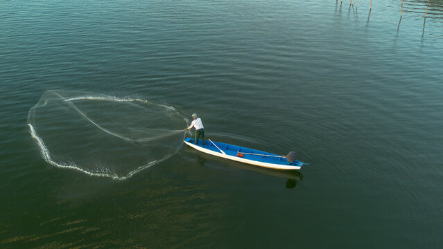 Aerial View of Traditional Fisherman Casting a Fishing Net from a Small Boat