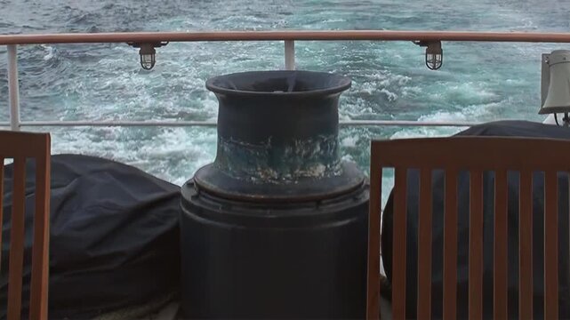 A sturdy vessel navigates the vast, untamed Arctic Ocean, its powerful stern creating a mesmerizing, foamy wake. The deck's strong railing and weathered equipment frame this chilling polar expedition.